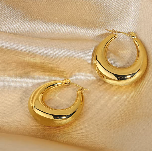 Gold hoop earrings on a beige satin background